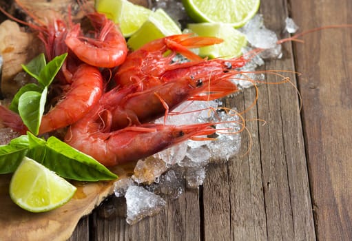 Raw shrimps with lime and basil over dark background