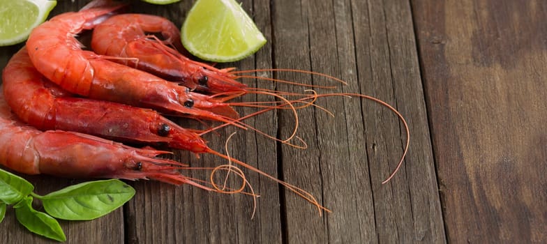 Raw shrimps with lime and herbs over dark background