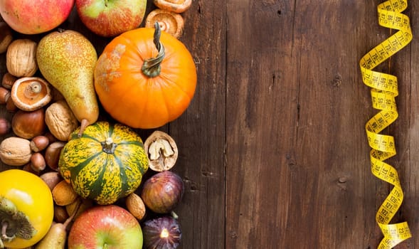 Autumn border made of fruits, vegetables, mushrooms, nuts and sunflower on a wooden table