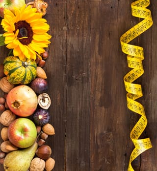 Autumn border made of fruits, vegetables, mushrooms, nuts and sunflower on a wooden table