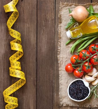 Black organic rice, vegetables and herbs on wooden background