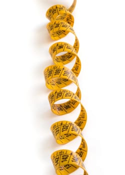 A coiled yellow measuring tape isolated on white