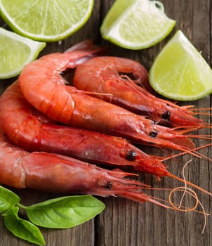 Raw shrimps with lime and herbs over dark background