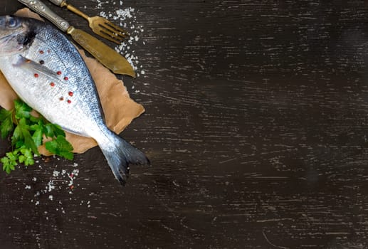 Fresh dorado fish, silver fork and knife and parsley