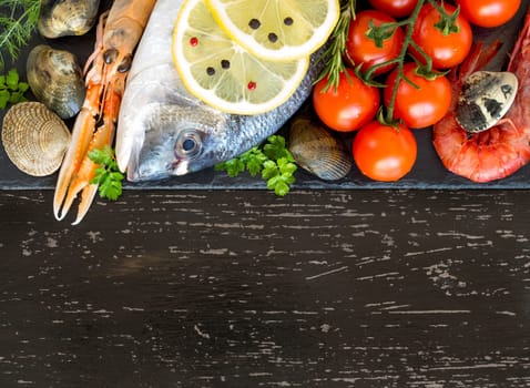Fresh dorado fish, seafood and vegetables on a dark background