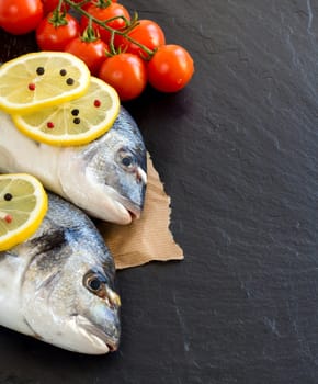 Fresh dorado fish and vegetables on dark vintage background