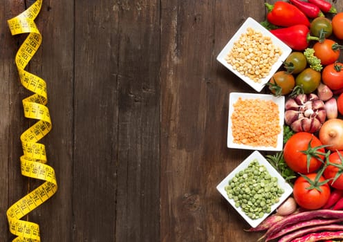 Legumes in bowls and vegetables on a wooden table
