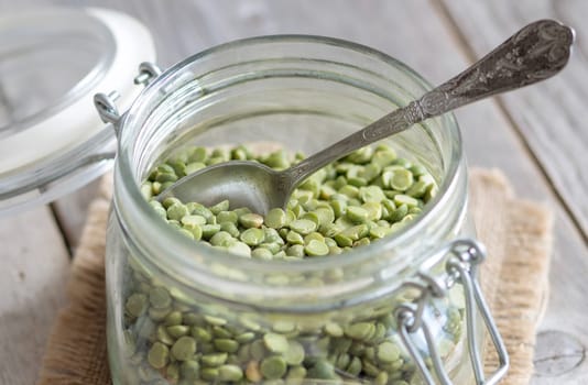 Green peas in a glass jar with a spoon