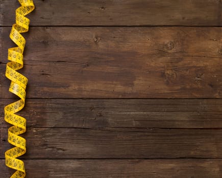 A coiled yellow measuring tape on a wooden table