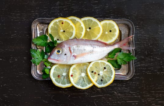 Fresh fish with lemon on vintage silver tray