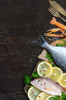 Fresh fish with seafood and vegetables on a wooden board isolated on white