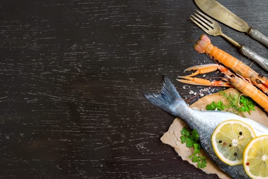 Fresh dorado fish and seafood on a dark vintage board