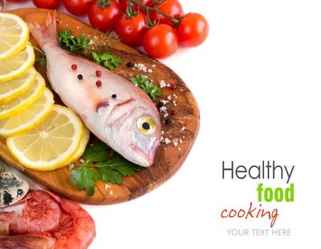 Fresh fish with seafood and vegetables on a wooden board isolated on white