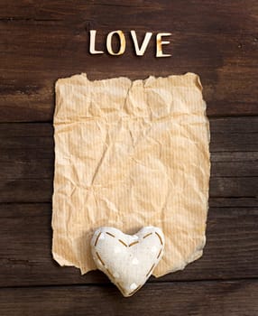 Old paper, heart and word Love on the wood background