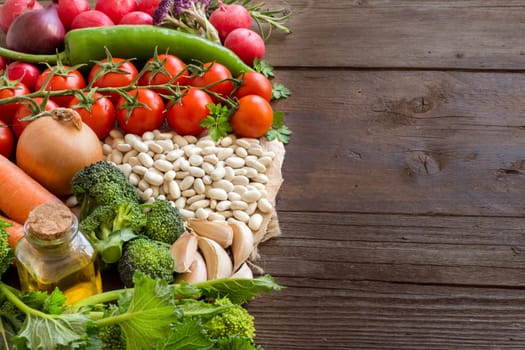 Pile of White beans and vegetables on a wooden bacground