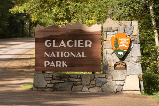 The sun hits a sign marking the entry to Glacier National Park