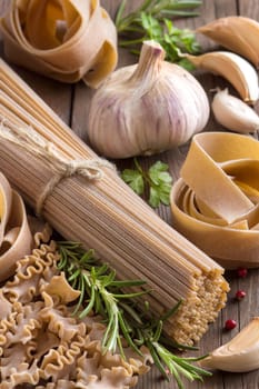 Whole wheat italian pasta with garlic and herbs on wood