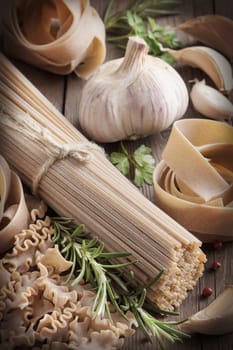 Whole wheat italian pasta with garlic and herbs on wood