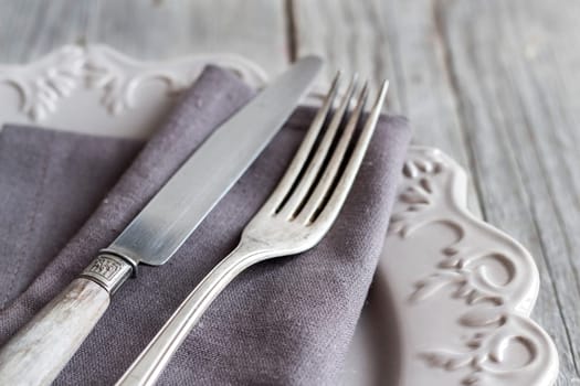 Vintage Table setting with napkin and plate on old wooden table