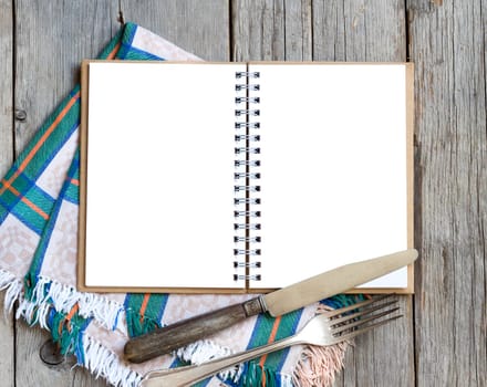 Blank cooking recipe book with fork, knife an napkin on wooden table