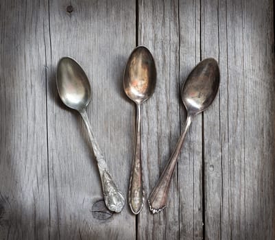 Vintage spoons with patina on old wooden table