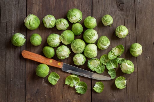 Brussels sprouts with leaves and knife on wood