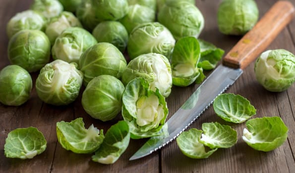 Brussels sprouts with leaves and knife on wood