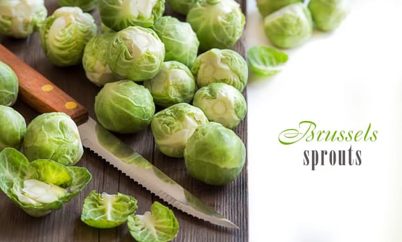 Brussels sprouts with leaves and knife on wood