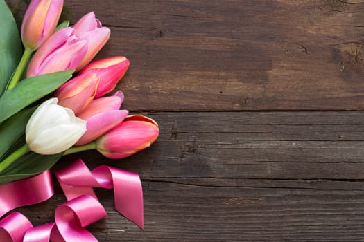 Pink and white tulips on dark wood background