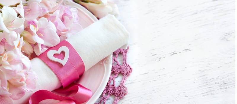 Festive wedding table setting with pink flowers and ribbon