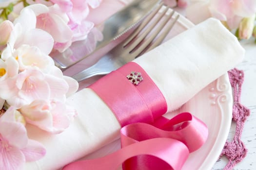 Festive wedding table setting with pink flowers and ribbon