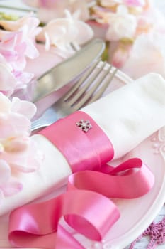 Festive wedding table setting with pink flowers and ribbon