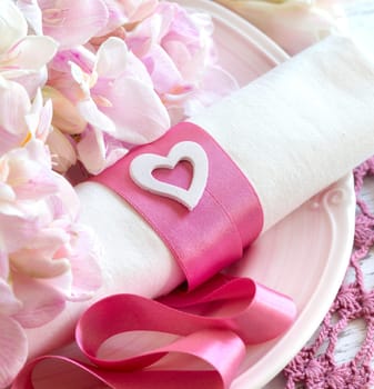 Festive wedding table setting with pink flowers and ribbon