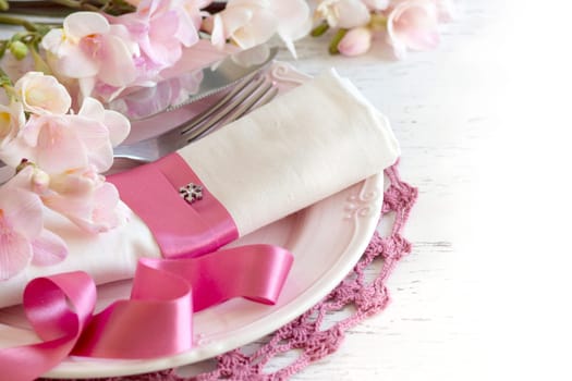 Festive wedding table setting with pink flowers and ribbon
