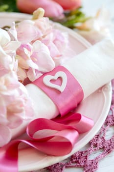 Festive wedding table setting with pink flowers and ribbon