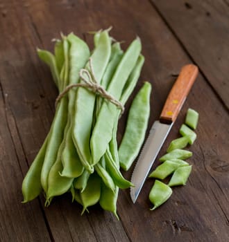 Piattoni green beans with knife on the old wooden table