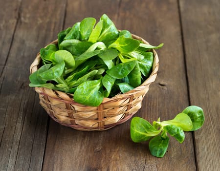 Field salad in a bowl on the old wooden table