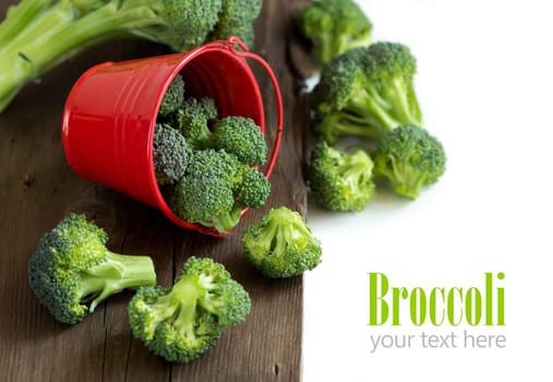 Fresh broccoli in red bucket on old wood