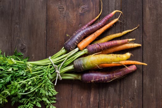 Fresh organic rainbow carrots with leaves on a wooden table