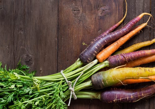 Fresh organic rainbow carrots on a wooden table