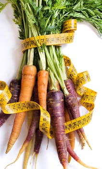 Fresh organic rainbow carrots and yellow measuring type