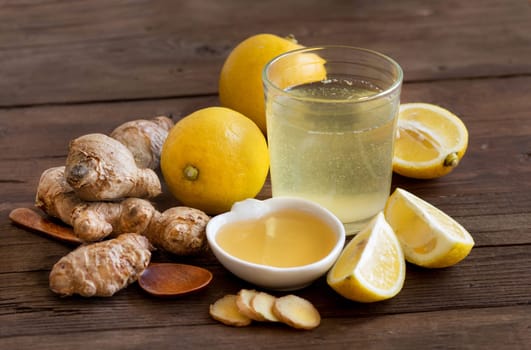 Honey, lemon and ginger tonic and ingridients on wood