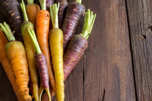 Fresh organic rainbow carrots on a wooden table