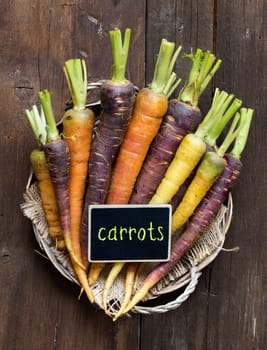 Fresh organic rainbow carrots and a small chalkboard on wood