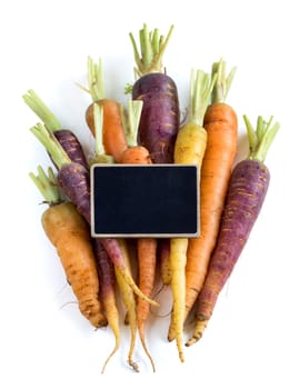 Fresh organic rainbow carrots with small chalkboard isolated on white