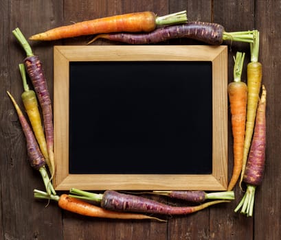 Fresh organic rainbow carrots and chalkboard on wood