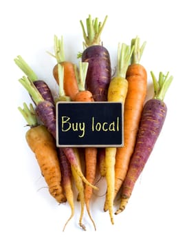 Fresh organic rainbow carrots with small chalkboard isolated on white