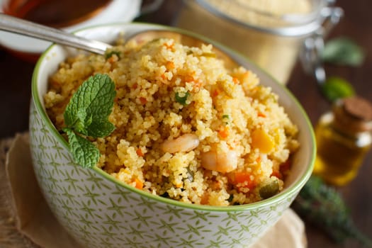 Couscous with shrimps and vegetables in a bowl close up
