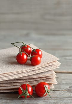 Raw lasagna sheets and cherry tomatoes on a wooden table close up