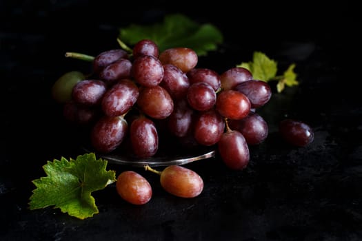Red grapes on a silver bowl on a dark Background